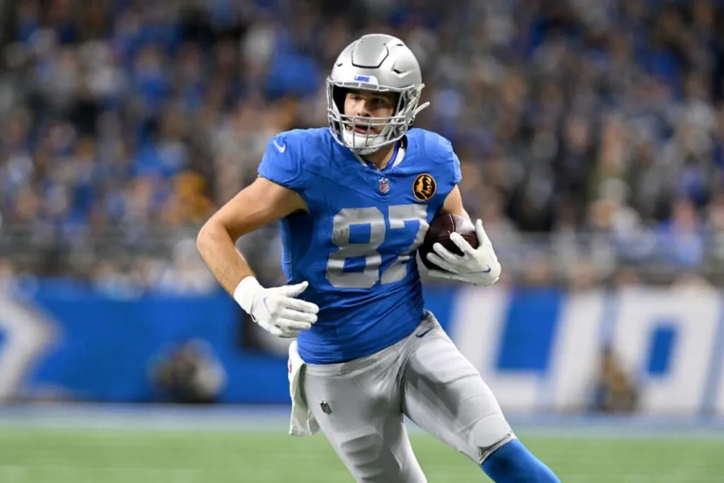a man in a blue American football uniform runs with a ball in his hands